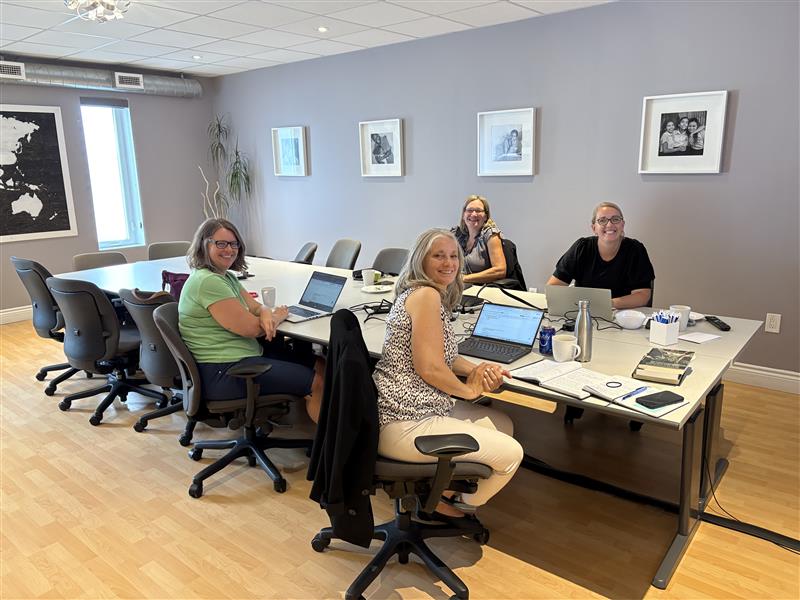 Smiling group of four women sitting at conference table in EduDeo's office.