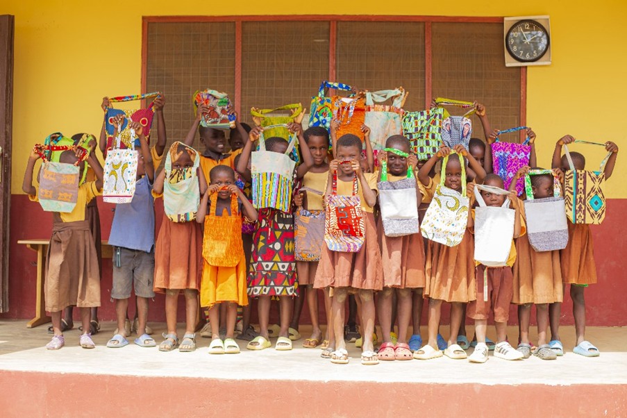Students holding up colourful cloth bags.