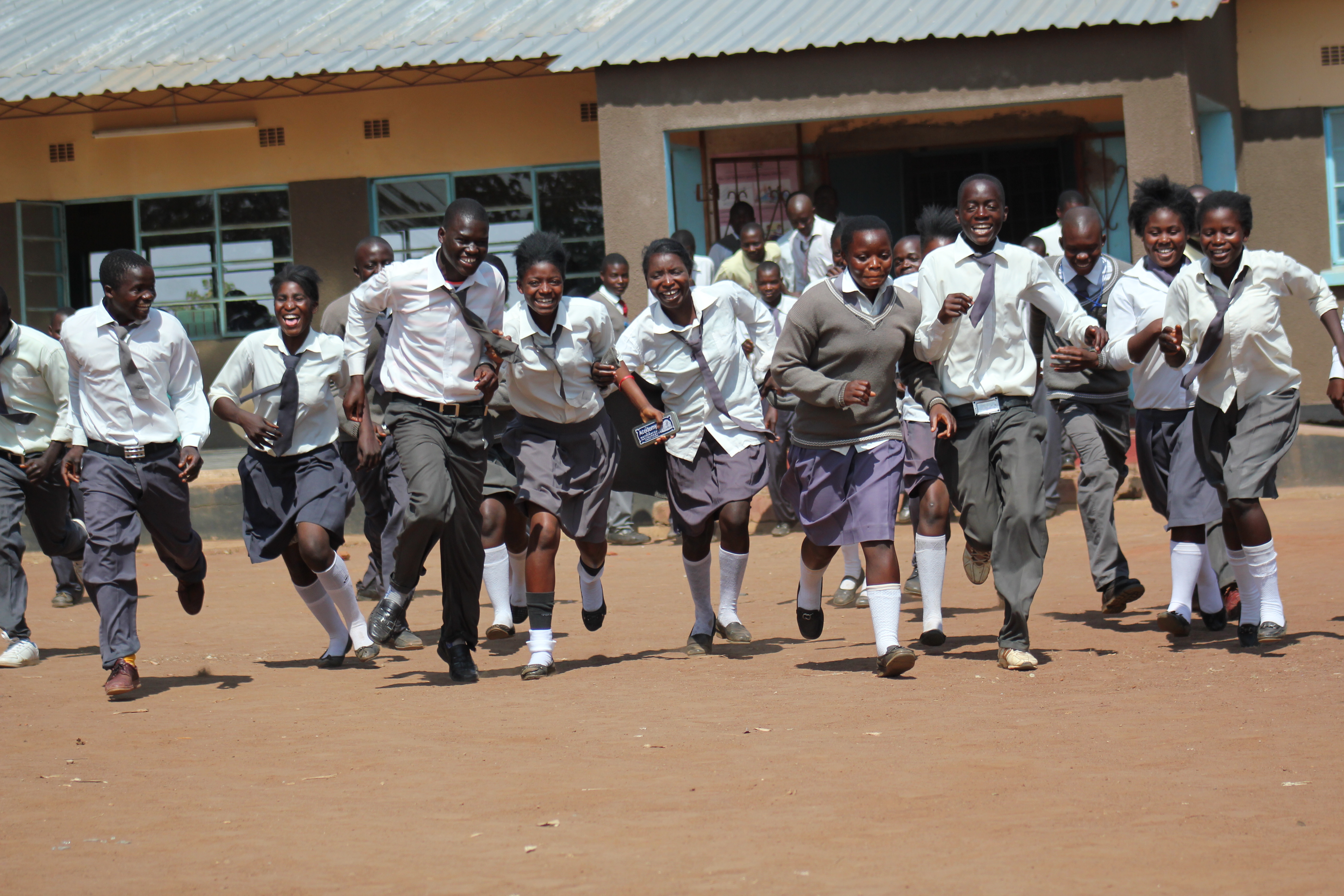 Students running towards the camera wearing uniforms