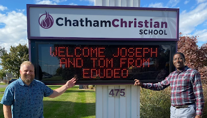 Tom and Joseph in front of Chatham Christian School sign.