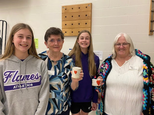 Two students with grandparents smiling over handmade mugs